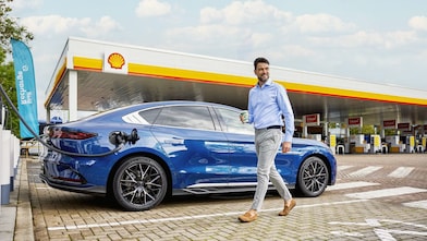 Mann lädt sein E-Auto an einer Shell Recharge Schnellladesäule an einer Shell Station