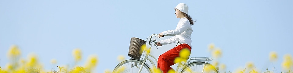 Eine junge Frau fährt mit dem Fahrrad über ein Sommerfeld.