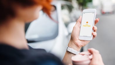 Eine Frau blickt auf ihr Smartphone mit der Shell Fleet App.