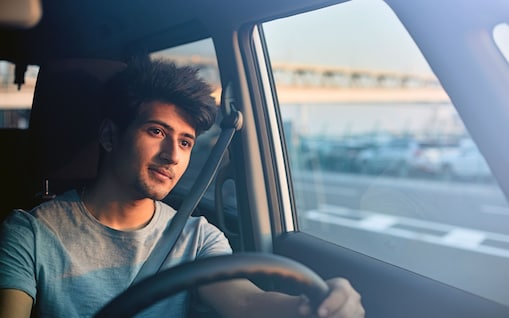 Ein junger Mann sitzt blickt aus dem Fenster des Autos.