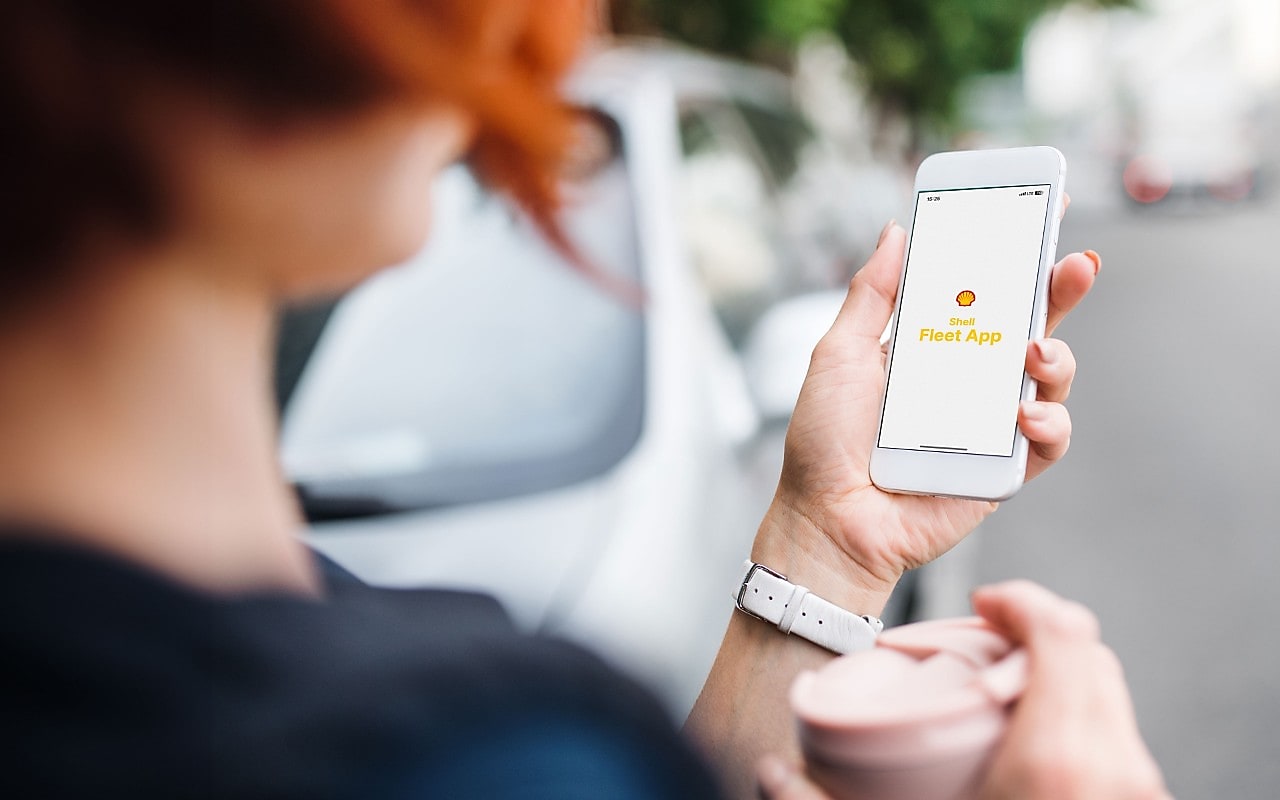 Eine Frau blickt auf ihr Smartphone mit der Shell Fleet App.