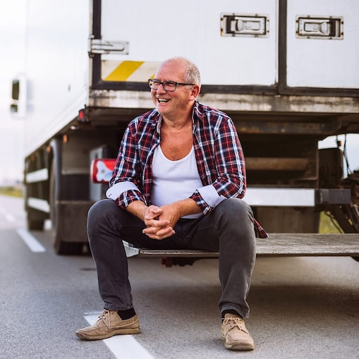 Ein Lkw Fahrer sitzt auf dem Heck seines Lkw.