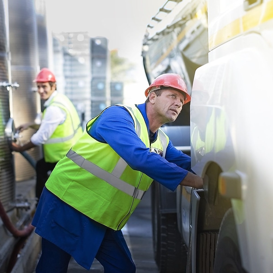 Ein Mann mit Warnweste überprüft den Lkw Reinigungsvorgang.