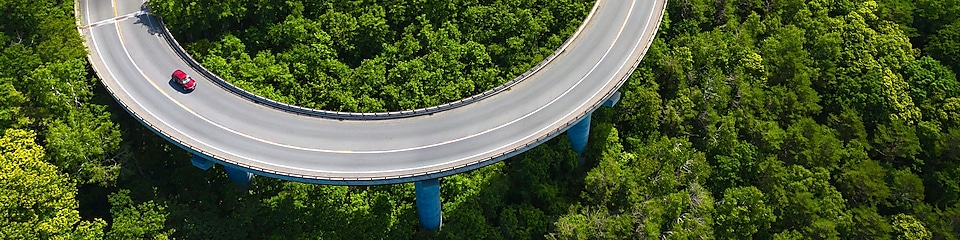 Ein Auto fährt auf einer Straße durch den Wald.