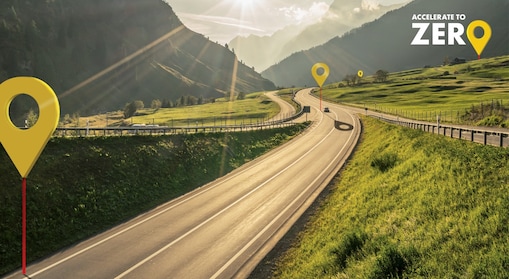 Eine Straße führt durch eine Bergregion. Die Überschrift auf dem Bild: Accelerate to zero.