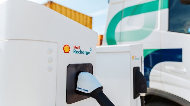 Nahaufnahme eines Ladesteckers eines Shell Recharge Ladedepots, im Hintergrund ein E-Lkw.