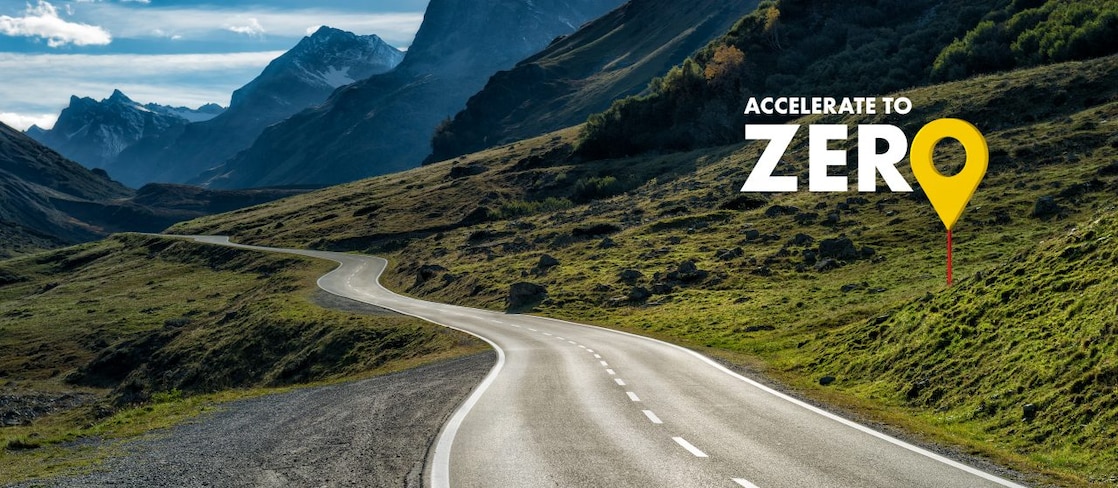 Eine Straße führt durch eine Bergregion. Die Überschrift auf dem Bild: Accelerate to zero. 