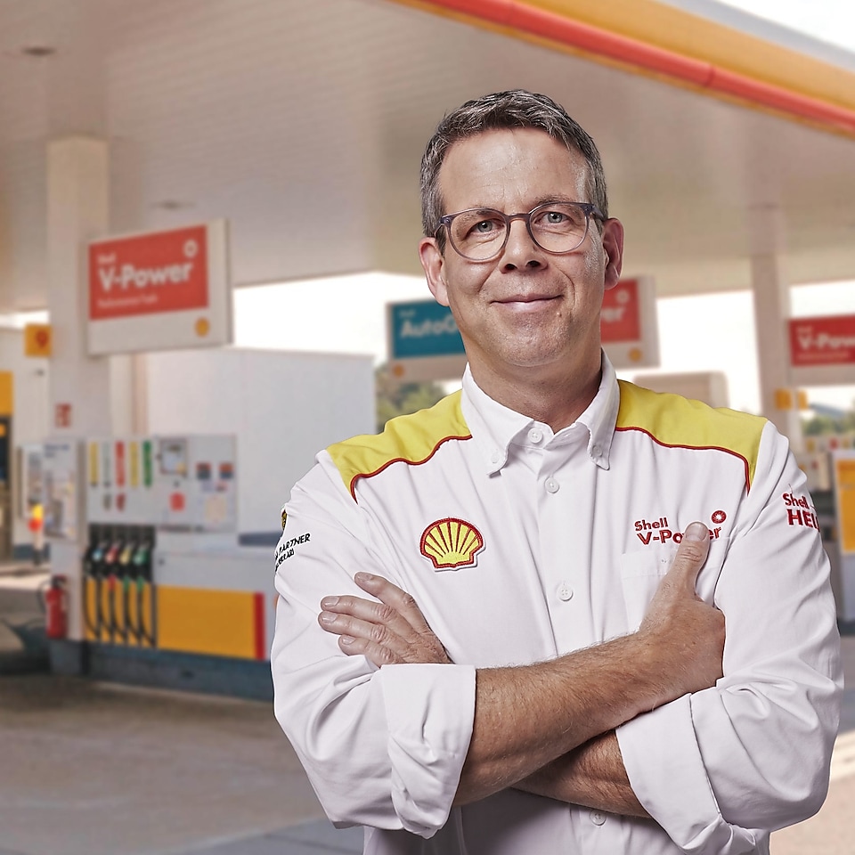 Zwei Mitarbeiter in Shell Dienstkleidung stehen auf einer Shell Tankstelle