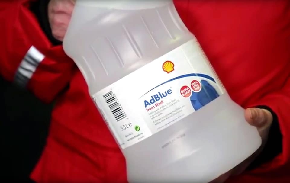 Ausschnitt Shell Tankwart hält AdBlue Flasche in den Händen. 