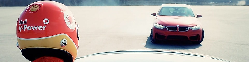 Roter BMW driftet um Mann mit Shell V-Power Helm