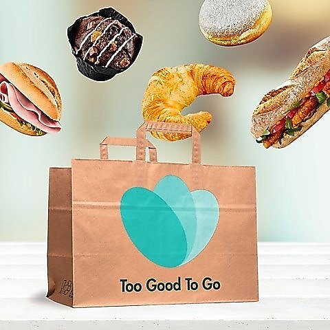 Too Good To Go Papiertüte mit darüber schwebenden Snacks wie ein Croissant und ein Muffin.