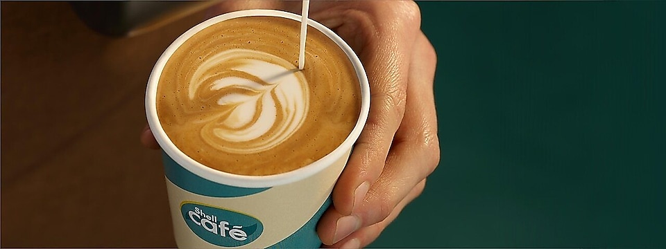 Hand hält Kaffee in Einwegbecher