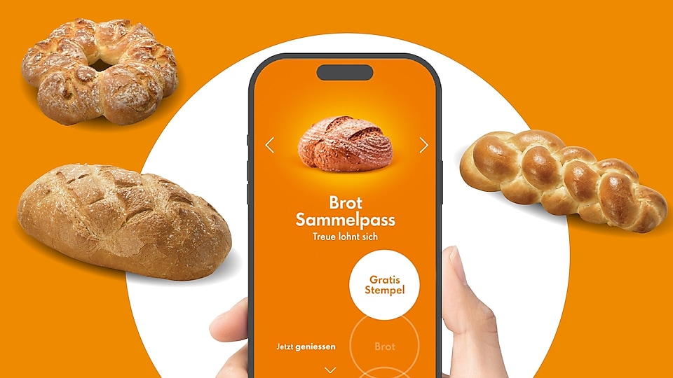 Ein Handy, das den Shell Brot Sammelpass zeigt, wird von einer Hand gehalten, im Hintergrund sind Brote zu sehen