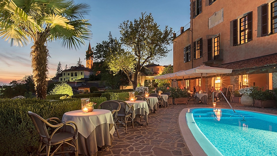 Ansicht eines Hotels in der Dämmerung mit Pool in einer südländischen Landschaft mit Palmen
