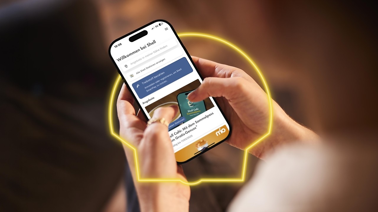 Frau hält in der Hand ein Handy mit geöffneter Shell App und sieht sich aktuelle Angebote an.
