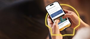 Frau hält in der Hand ein Handy mit geöffneter Shell App und sieht sich aktuelle Angebote an.