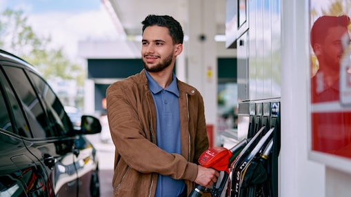 Un jeune homme fait le plein de sa voiture dans une station Shell
