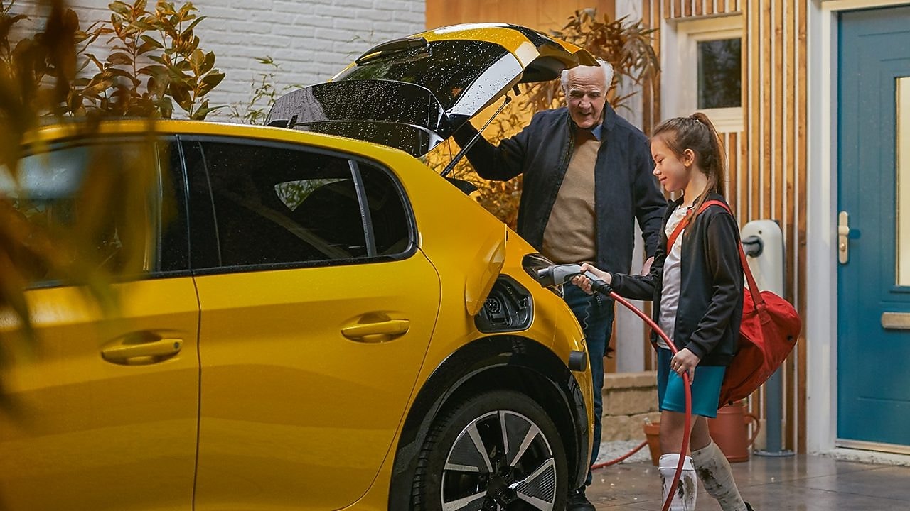 Une jeune fille et son grand-père rechargent une voiture électrique à la maison