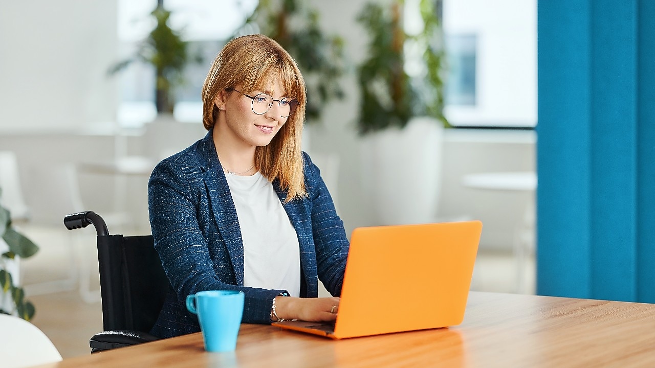Une personne en fauteuil roulant travaillant sur un ordinateur portable dans un bureau