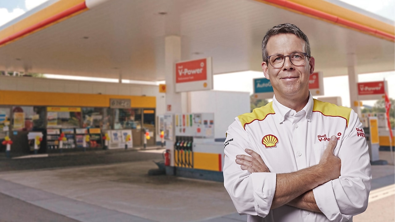 Un gérant de station-service Shell devant une station Shell