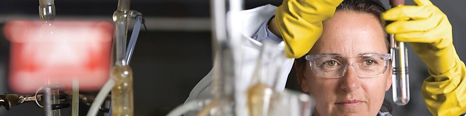 Une femme portant des lunettes de sécurité effectue une analyse dans un laboratoire.