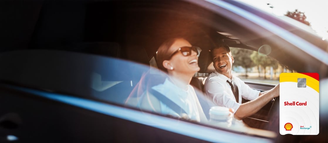 Une femme et un homme sont assis dans la voiture et rient. La carte Shell est visible.