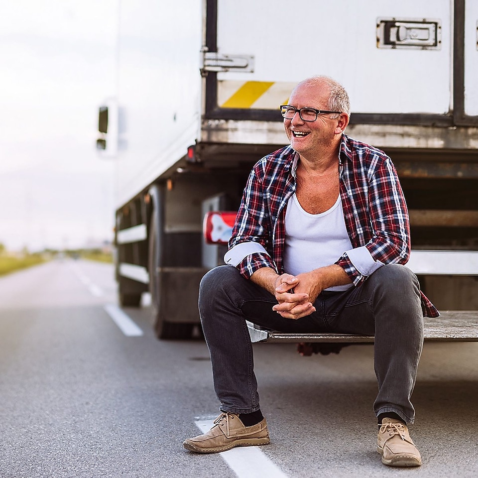 Un chauffeur de camion est assis à l'arrière de son camion.