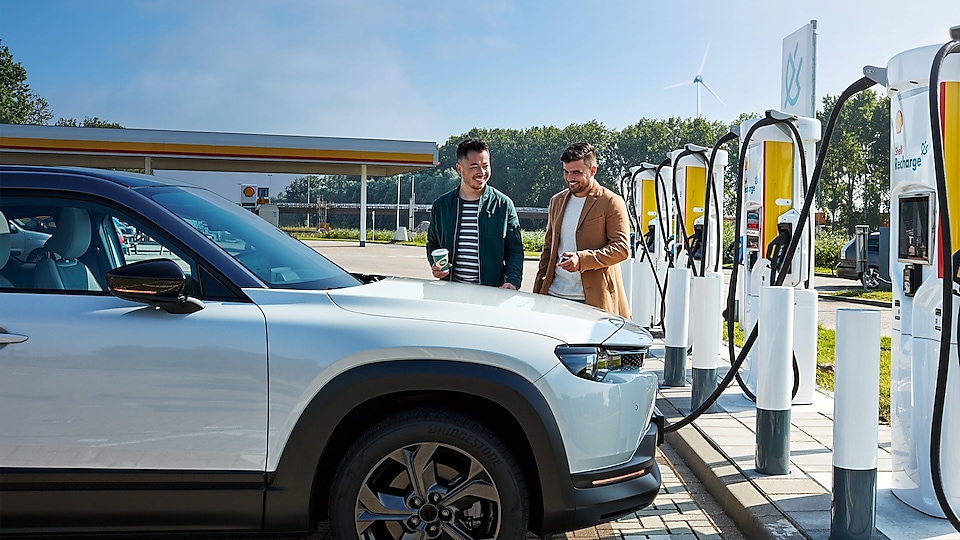 Zwei Männer stehen mit ihrem E-Auto an einer Shell Recharge Ladestation.