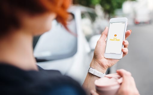 Une femme regarde son smartphone avec l'application Shell Fleet.