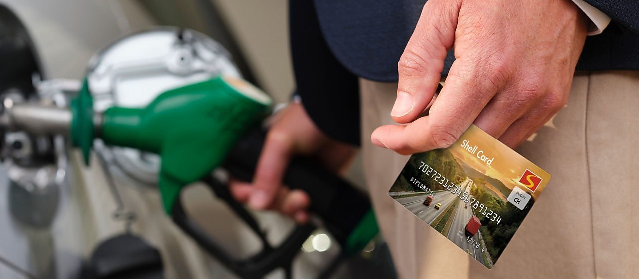 Ein Mann hält beim Tanken die Shell Card Diplomatic in der Hand
