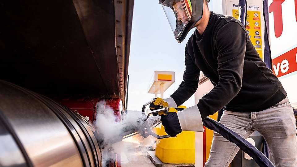 Ein Fuhrpark-Manager und Fahrer unterhalten sich an einer Shell LNG Station vor einem parkenden Lkw.