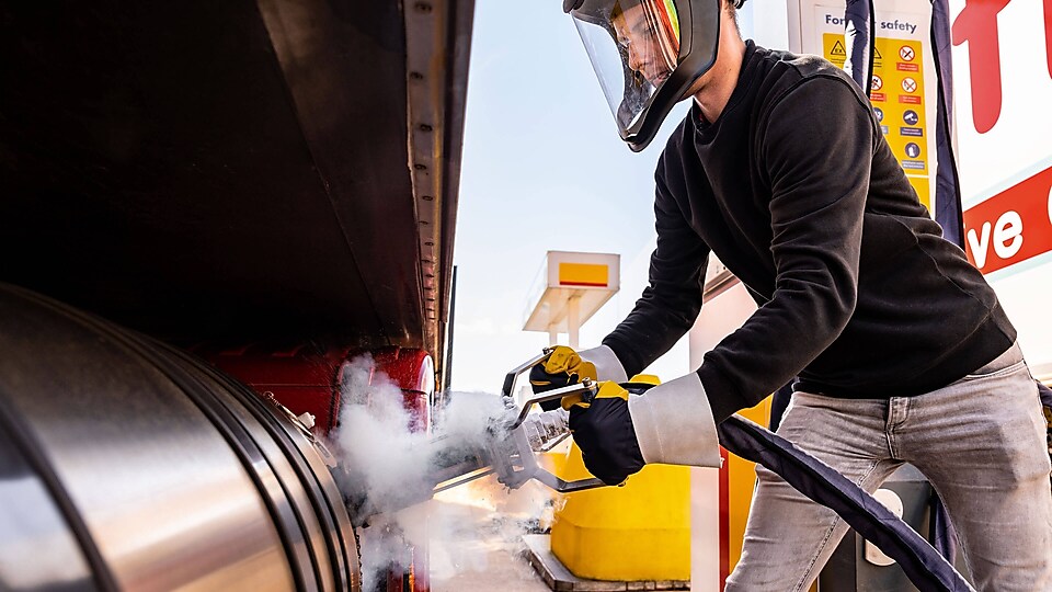 Ein Mann tankt LNG an einer Shell Station und trägt dabei eine Schutzausrüstung.