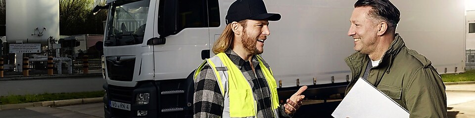 Ein Fuhrpark-Manager und Fahrer unterhalten sich an einer Shell LNG Station vor einem parkenden Lkw.