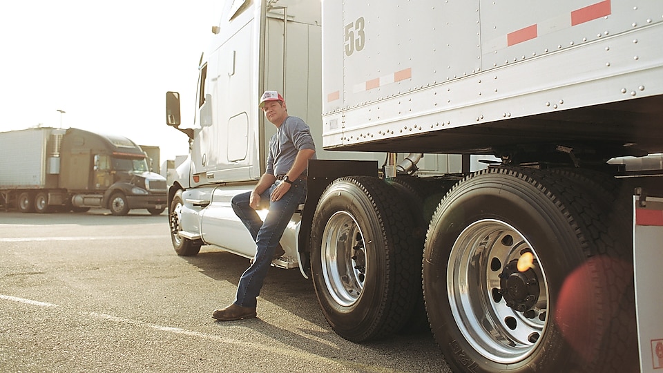 Driver leaning on truck