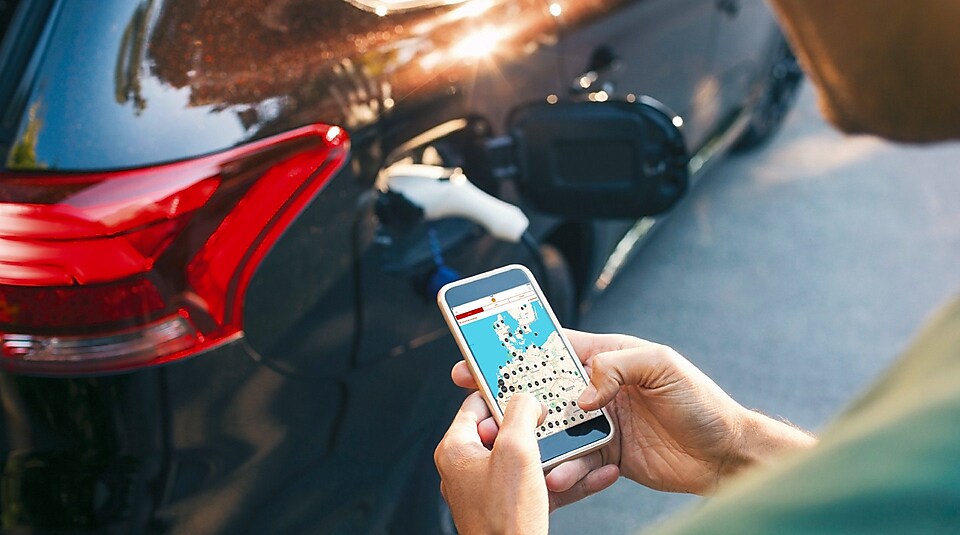 Un client utilise une application de navigation pendant que sa voiture électrique charge