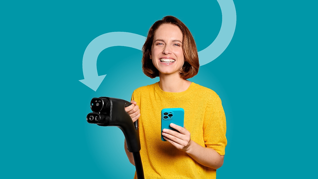 Femme souriante en haut jaune tenant un câble de recharge et un smartphone devant un fond turquoise.