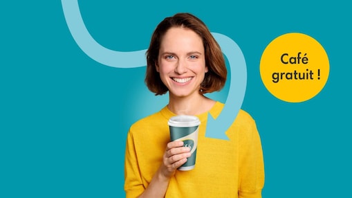 Une jeune femme en pull jaune tient en souriant un gobelet de café Shell Café devant un fond bleu turquoise. À côté d’elle se trouve un cercle jaune avec l’inscription « Café gratuit ! » et une flèche courbée pointe vers le gobelet.