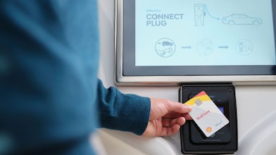 Personne tenant une carte Shell Card devant une borne Shell Recharge