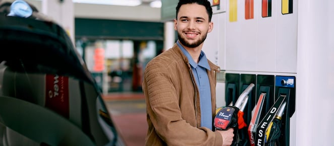 Un jeune homme fait le plein de sa voiture dans une station Shell