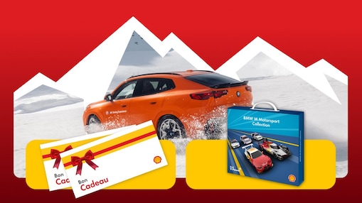 Une BMW orange roule à travers un paysage montagneux enneigé, encadré par des silhouettes de montagnes blanches sur un fond rouge. Au premier plan figurent des cartes-cadeaux Shell ainsi que le coffret de voiture miniature de la « BMW M Motorsport Collection