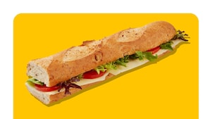 Sandwich demi-baguette avec fromage, salade et concombre sur fond jaune.