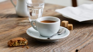 Un espresso servi dans une tasse en porcelaine Shell Café posé sur une table en bois