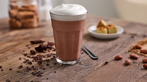 Un espresso servi dans une tasse en porcelaine Shell Café posé sur une table en bois