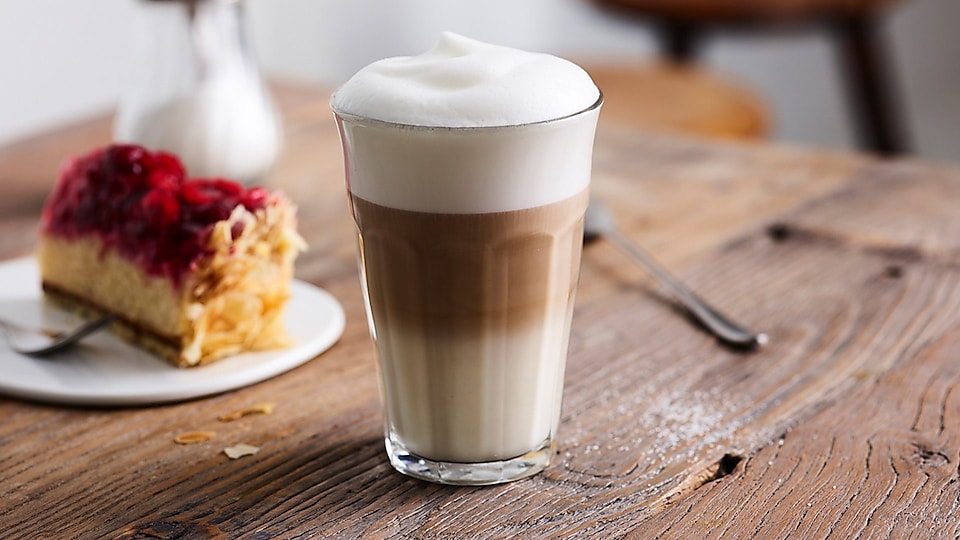 Glass with latte macchiato on table