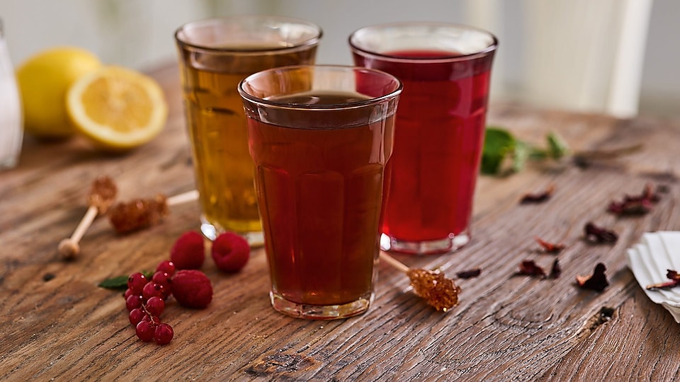 three glasses with tea on wooden table.